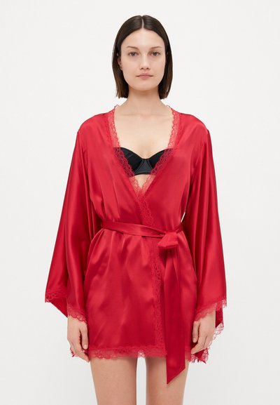 Červený saténový kimono župan s krajkovým lemováním, širokými rukávy a odpovídajícím opaskem, nošený přes černou podprsenku. Hladká textura a elegantní design.