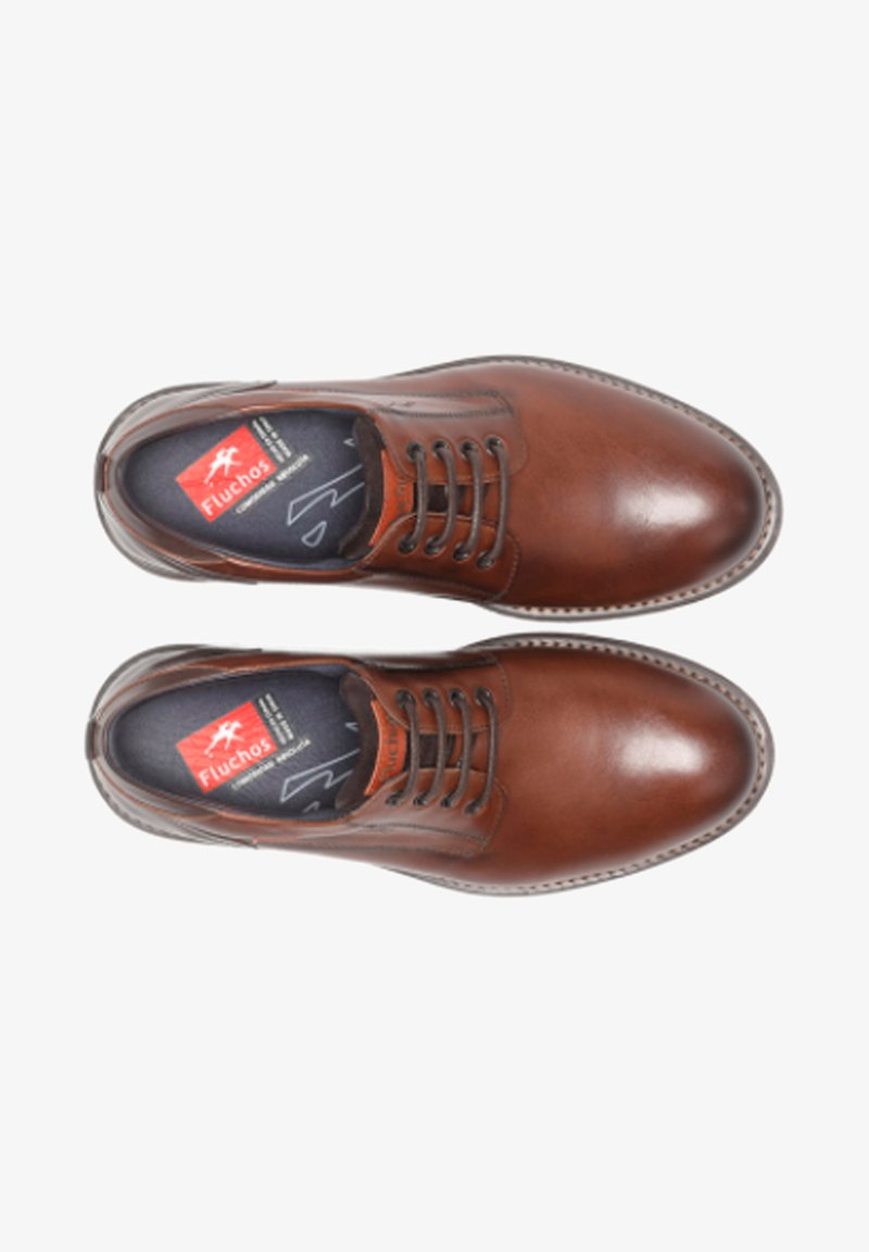 Zapatos de cuero marrón con punta redonda, diseño de cordones, costuras visibles y una plantilla texturizada que presenta el logo de Fluchos.