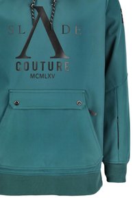 Een tealkleurige hoodie met een voorvak dat wordt afgesloten met twee zwarte knopen, zwarte trekkoorden en zwarte tekst met de woorden "SLADE COUTURE MCMLXV".