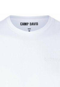Biała bawełniana koszulka z okrągłym dekoltem. Posiada wytłoczone logo "CAMP DAVID" na piersi oraz metkę z rozmiarem M. Gładka tekstura.