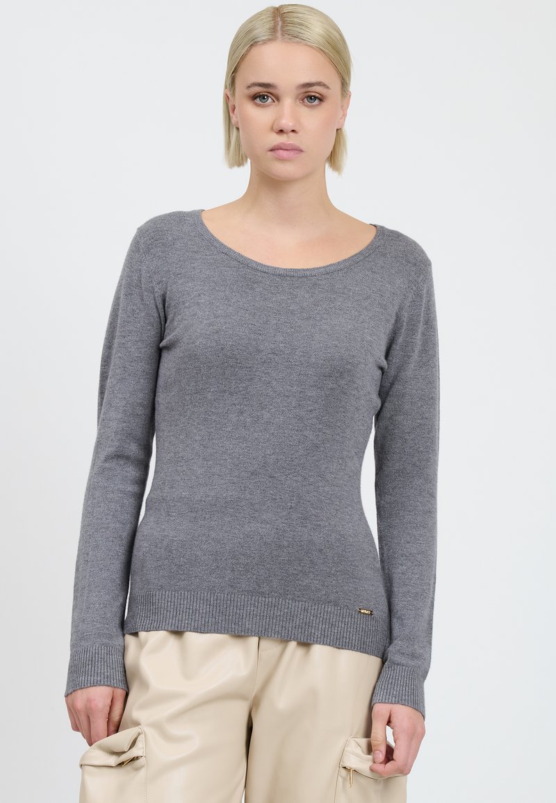 Maglione grigio a maglia con maniche lunghe, scollatura rotonda e orlo a coste. Presenta un piccolo logo dorato vicino al fondo.