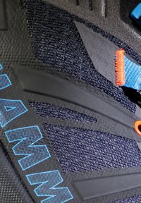 Svart klatresko med teksturert mesh, blå og oransje aksenter, gummisåle og forsterket hæl med en fremtredende logo i blå.