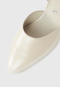 Παπούτσι με μυτερή μύτη από δέρμα σε ανοιχτό μπεζ χρώμα, με λεία υφή και σχ έδιο με κομμένο πλαϊνό μέρος. Το εσωτερικό διαθέτει απαλό επένδυση.