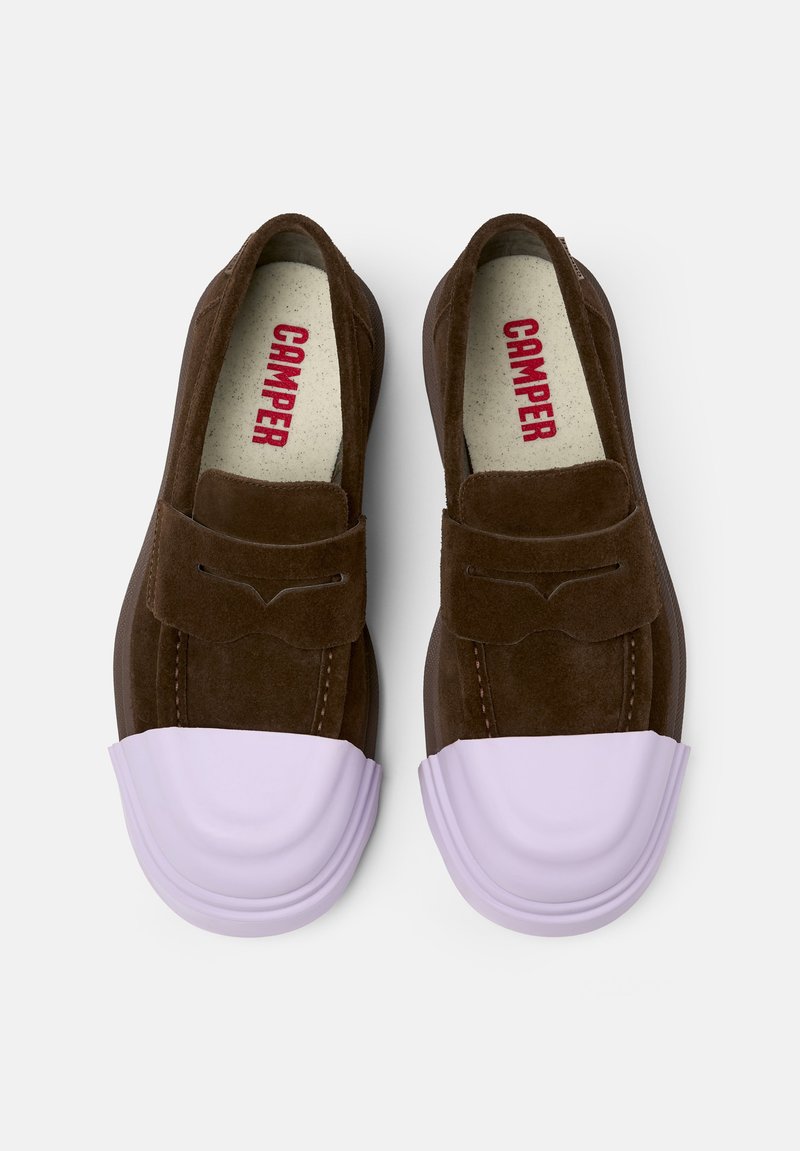 Ballerines en daim marron à enfiler avec un capuchon en caoutchouc lavande, présentant un rabat décoratif à l'avant et la marque rouge "CAMPER" à l'intérieur.