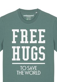 Teal katoenen t-shirt met korte mouwen, met grote witte tekst: "FREE HUGS" boven "TO SAVE THE WORLD" in een strakke lettertype.
