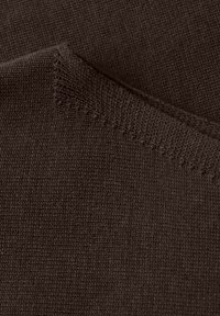 Gros plan sur un tissu tricoté marron foncé montrant une couture texturée et un motif de maille fine.