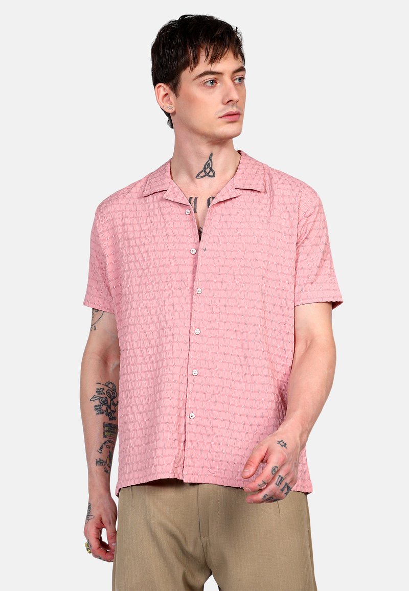 Camisa de botón de manga corta en color rosa con un patrón de cuadrícula texturizado, hecha de tejido ligero. Presenta un cuello con muesca y botones visibles.
