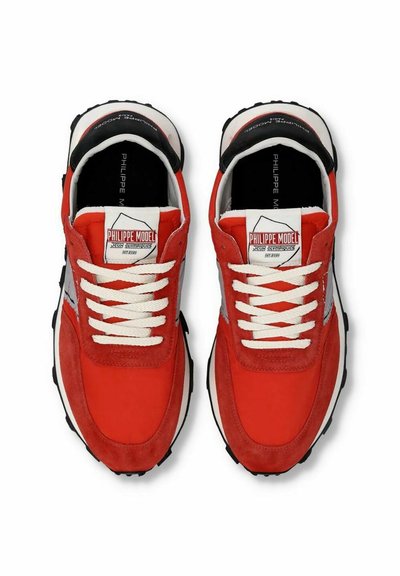 Sneaker in suede rosso con lacci bianchi, caratterizzati da un tallone nero e dettagli grigi. Presentano il marchio sulla linguetta e una suola testurizzata.