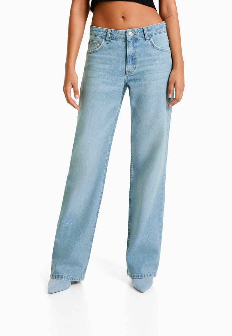 Light blue wide-leg jeans with a high waist, five pockets, and a faded texture. Features a zip fly and metal button closure.