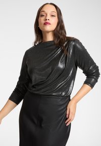 Czarna metaliczna bluzka z drapowanym wzorem i długimi rękawami, zestawiona z dopasowaną czarną spódnicą w stylu skóry. Gładka tekstura i elegancki wygląd.