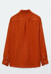 Chemise à manches longues en lin orange brûlé. Présente un col, des poignets boutonnés, une pince au dos et une texture lisse avec un design décontracté.