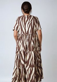 Brown and cream zebra print maxi dress with short sleeves, tiered design, flowing silhouette, soft fabric, and a round neckline.