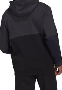 Sweat à capuche noir et gris foncé, avec un design bicolore, tissu doux, manches longues et poche kangourou.