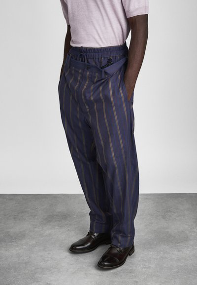 Navy striped trousers featuring a relaxed fit, elastic waistband, and side pockets. Paired with black leather shoes.