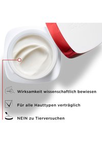 Vit kräm i en rund burk med ett rött lock, som visar en jämn konsistens och en synlig virvel av produkten. Texten framhäver effektivitet och hudvänlighet.