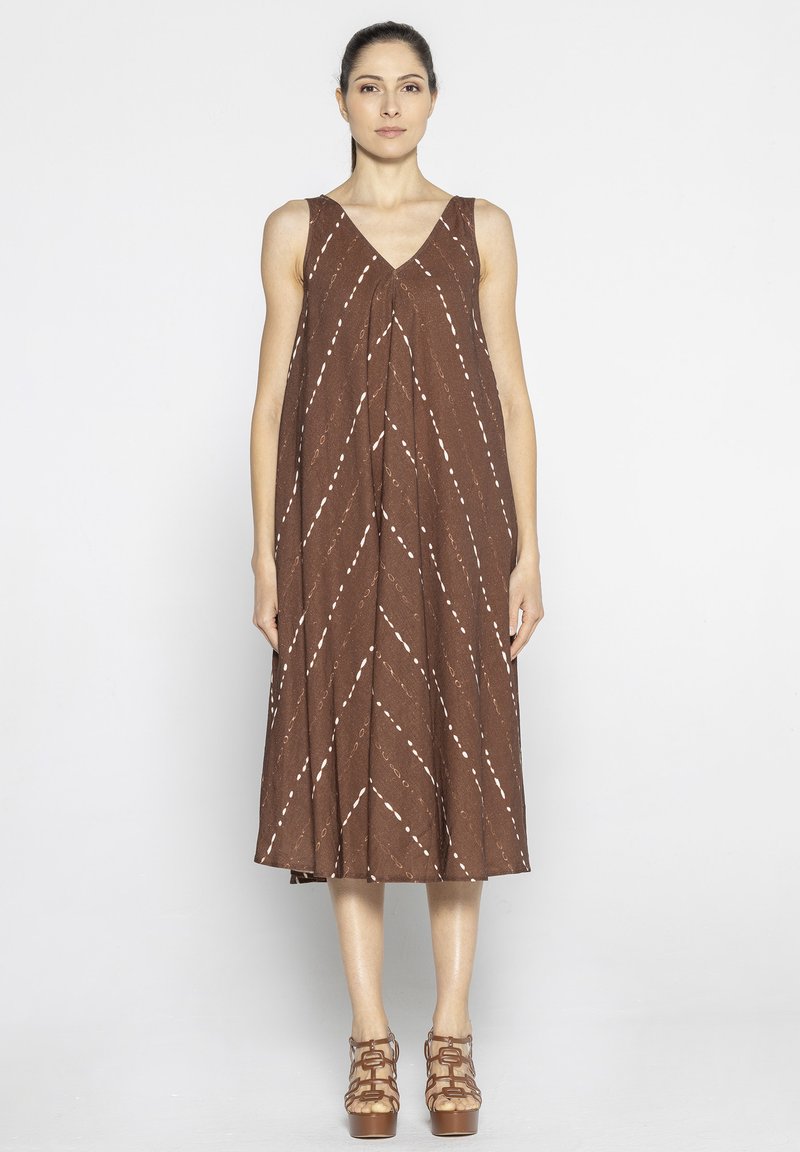 Brązowa, bezrękawnikowa sukienka z dekoltem w kształcie V, z nieregularnymi, białymi ukośnymi paskami. Krój ma luźny fit, sięgający do kolan.