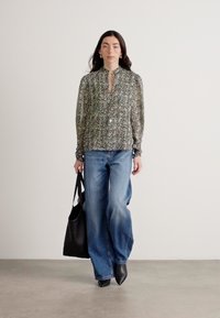 Bluză cu model floral, cu mâneci lungi, deschidere cu nasturi și detaliu de nod la gât, asortată cu blugi de tip wide-leg, cu talie înaltă, de culoare albastră, și o geantă mare neagră.