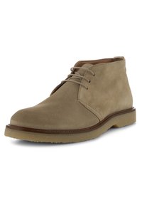 Stivale chukka in suede beige con una texture liscia, punta arrotondata e lacci in pelle. Presenta una leggera suola in gomma e cuciture marroni a contrasto.
