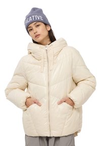 Jasno-beżowa kurtka puchowa z kapturem, z zapięciem na zamek błyskawiczny i dwoma przednimi kieszeniami. Posiada ukośne przeszycia i połyskującą fakturę.