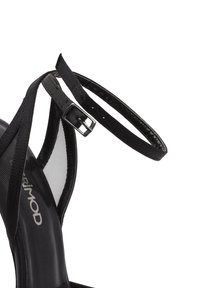 Zwarte high-heeled sandaal met kruislingse banden, verstelbare enkelband, elegante textuur en glanzende afwerking. Zilveren hardware detail op de band.
