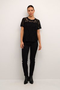 Zwarte kanten top met een scalloped halslijn en korte mouwen, gecombineerd met zwarte skinny pants en enkellaarsjes. De stof heeft een bloemenpatroon.