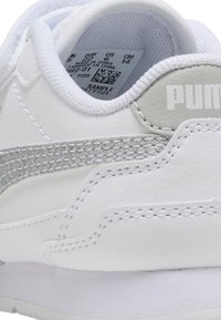 Sneaker bianche con tomaia in pelle liscia, accenti argentati, una striscia laterale texturizzata e una collarino imbottito. Dettagli dell'etichetta visibili all'interno.