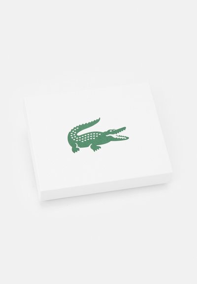 Boîte rectangulaire blanche présentant un design de crocodile vert avec des écailles triangulaires et une bouche ouverte. Texture lisse avec un motif subtil.