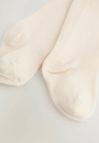 Béžové ponožky strednej dĺžky vyrobené z mäkkého, elastického materiálu. Vyznačujú sa hladkým povrchom s ryhovanými detailmi a zosilnenými špičkami.