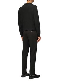 Donker trui met een kraag, gecombineerd met zwarte broek. De outfit heeft een soepele textuur en een slim-fit ontwerp, aangevuld met zwarte schoenen.