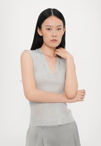 Maglione grigio senza maniche con scollatura a V e tessuto a coste. Il design presenta dettagli a spacco sulle spalle, creando una silhouette aderente.