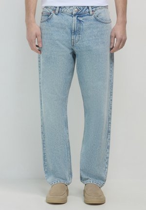 Light blue denim jeans with a slightly loose fit, featuring a classic five-pocket design and a button fly. Soft texture and faded finish.