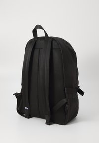 Sac à dos noir avec un panneau arrière en maille texturée, des bretelles rembourrées et des sangles latérales réglables. Doté d'une poignée de transport supérieure.