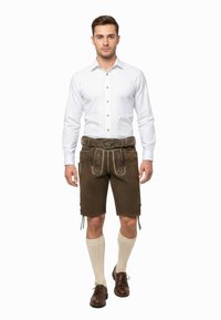 Mäns traditionella kläder med en vit skjorta med vertikala veck, bruna läderlederhosen, stickade krämfärgade strumpor och bruna skor med snören.