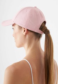 Lichtroze baseballpet met een gebogen klep, textuurstof, verstelbare achterband en gestikte details. Voorzien van een opening voor een paardenstaart.