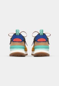 Rear view of colorful sneakers featuring blue, orange, and yellow materials, textured accents, patterned laces, and a cushioned sole.