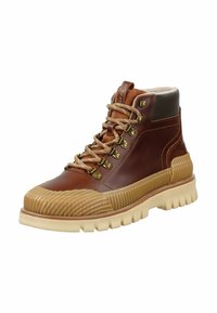 Brązowy skórzany but z teksturowaną gumową podeszwą, złotymi oczkami i beżowymi sznurowadłami. Posiada wyściełany kołnierz oraz paskowany detal na palcach.