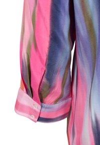 Chemise colorée à manches longues avec un motif fluide, présentant des nuances de rose, bleu et vert. Tissu doux avec poignets à boutons et texture lisse.