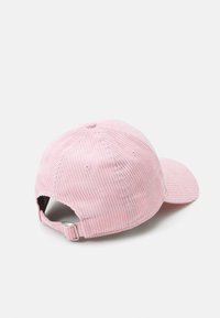 Boné de baseball em courduroy rosa com formato arredondado, viseira pré-curvada e tira metálica ajustável na parte de trás. Tecido texturizado em costura corduroy.