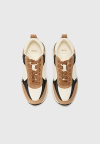 Sneakers con una toma superiore crema, dettagli in pelle nera, sovrapposizioni in suede marrone e lacci marroni. Logo visibile sulla soletta.