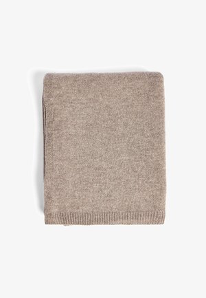 Zložený béžový sveter vyrobený z mäkkej pleteniny. Má štruktúrovaný povrch a rebrovaný lem. Kompaktne tvarovaný v obdlžnikovom tvare bez viditeľných vzorov.