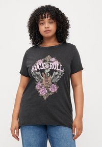 T-shirt graphique noir avec un design "Rock & Roll" comprenant une guitare, des ailes et des roses roses. Manches courtes et col rond.
