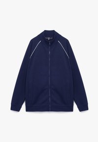 Chaqueta de chándal azul marino con cierre de cremallera y cuello alto, dos bolsillos laterales y costuras en blanco contrastante a lo largo de las costuras de los hombros. Tejido suave y texturizado.