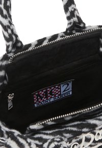 Un sac fourre-tout en tissu à motifs noir et blanc avec fermeture éclair, poche intérieure et étiquette "MC2 SAINT BARTH" sur la doublure.
