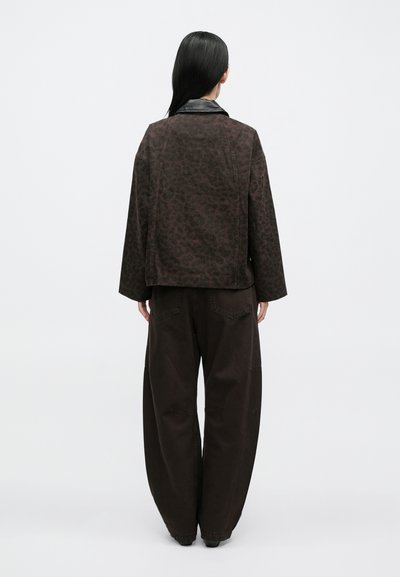 Jachetă maro cu textură, imprimeu leopard și guler din piele, asortată cu pantaloni maro cu picioare largi. Vedere din spate.