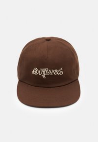 Brun keps med böjd skärm, med broderad text "Outlanes" i krämfärg. Tillverkad av tyg med slät textur. Enkel design.