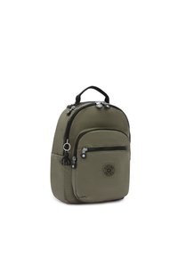 Zaino in nylon verde oliva con forma arrotondata, doppie cerniere, tasca frontale e un piccolo accento a forma di portachiavi. Presenta un patch con logo.