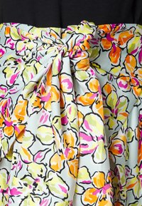 Tissu à motif floral avec de grandes fleurs roses, orange et vertes sur un fond bleu clair, noué à la taille. Texture lisse.