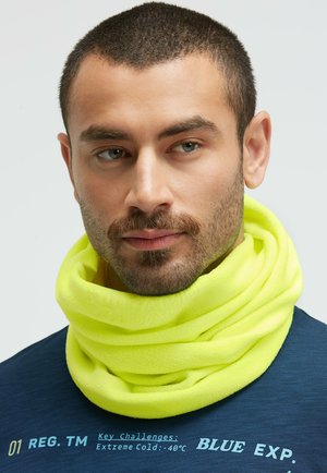 Neon yellow fleece neck gaiter with a soft texture, layered design, and a snug fit, worn over a dark blue shirt with printed text.