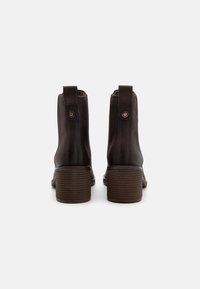 Bottines en cuir marron avec un talon empilé, dotées d'une languette à l'arrière, de coutures subtiles et d'un détail texturé au niveau du talon.