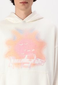 Kapuzensweatshirt in Off-White, mit einem gradienten Sonnenmotiv in pinken und orangefarbenen Tönen, akzentuiert mit zarten blauen Farbtönen und einer Fronttasche.